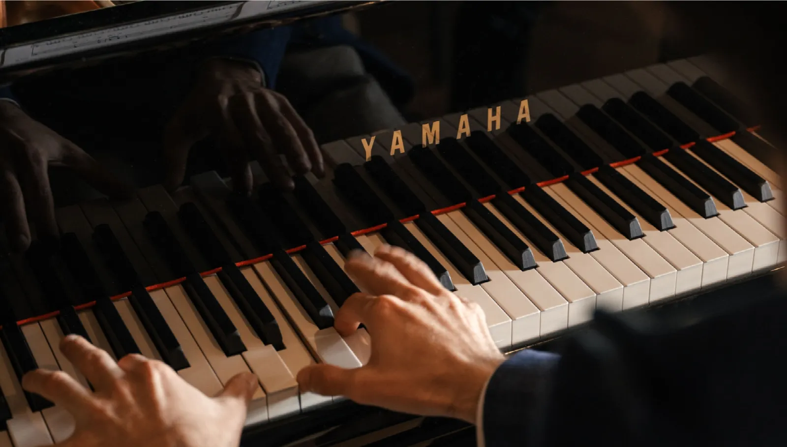 Pianist spielt auf einem Yamaha-Flügel mit aufgeschlagenen Notenblättern im Kulturraum des Cyprianerhofs